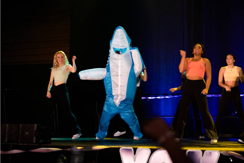 A student in a shark costume on stage.